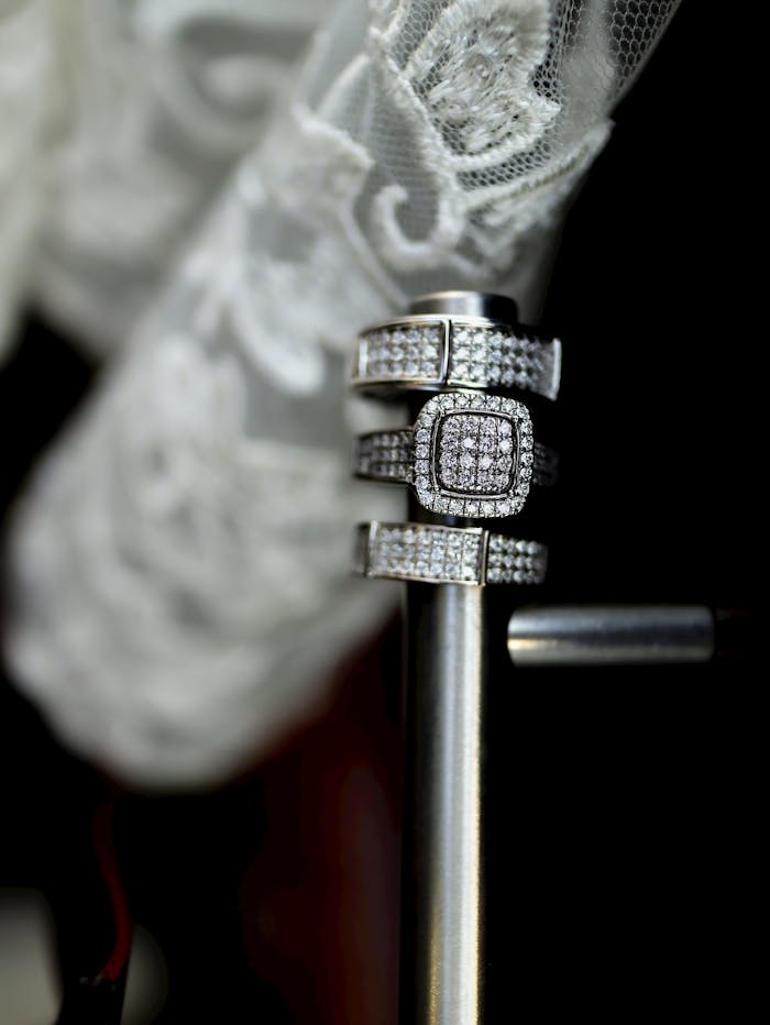 Close-up of elegant silver rings adorned with diamonds, showcasing intricate design against a lace backdrop.