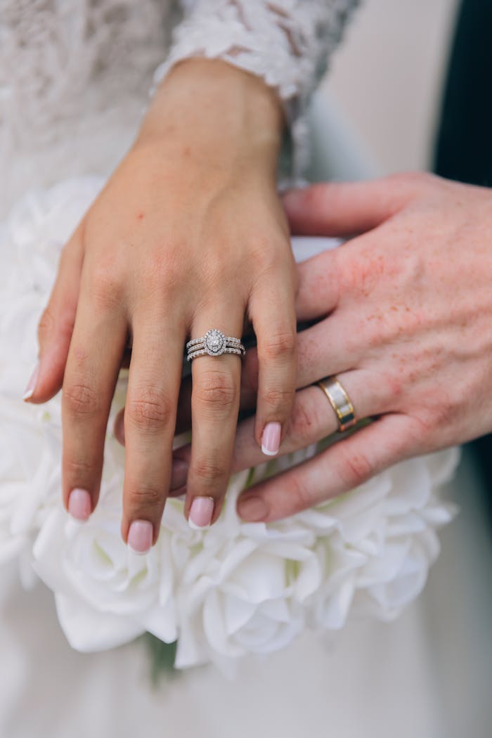 Close-up of bride and groom's hands showcasing elegant wedding and engagement rings.
